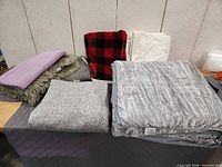 Assorted blankets, rugs, and quilt displayed on table