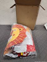Inflatable lion sprinkler sealed in plastic beside open cardboard box