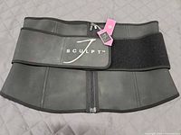 Front view of black J Sculpt waist trainer showing zipper and Velcro belt