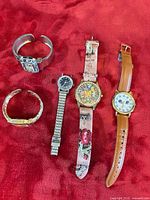 Group shot of all five watches laid out on red fabric
