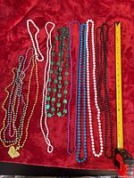 All thirteen bead necklaces laid flat with measuring tape for scale