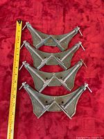 Four metal corner clamps laid out with measuring tape for scale