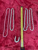 Four bead necklaces laid beside measuring tape