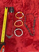 Overview of necklace, earrings, three bracelets and chain hairpiece with tape measure for scale