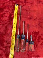 Four amber-handled Craftsman slotted screwdrivers alongside tape for scale