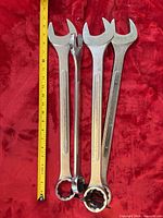 Front view of four large combination wrenches alongside tape for scale