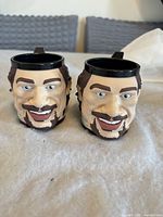 Front view of both sculpted face mugs
