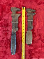 Two monkey wrenches beside measuring tape for scale
