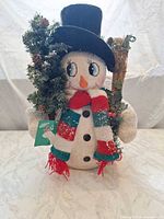 Front view of knit fabric snowman with hat, scarf, greenery wreath and broom