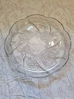 Top view of clear pressed glass platter showing full shape and scalloped edge
