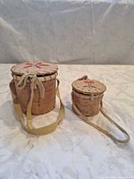 Two birch bark baskets with lids and straps side by side