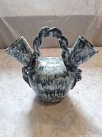Front view of blue-green marbled double-spout glazed ceramic vase with twisted handle
