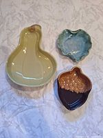 Three ceramic dishes laid out: pear, scalloped, acorn