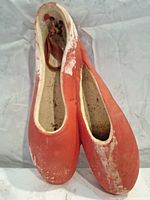 front view of red chalkware ballet slippers showing paint loss