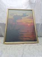 Angled view of framed seascape sunset print in gold frame