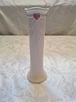 Front view of white porcelain bud vase with pink heart accent