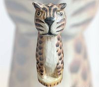 Front view of carved wooden leopard showing facial details and paint