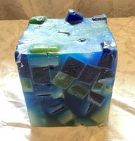 Front view of blue and green cube candle showing embedded blocks and wick