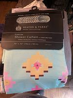 Front view of packaged Heaton & Parke shower curtain showing label, size, pattern and included hooks