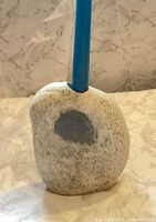Front view of river rock candle holder with blue taper candle inserted