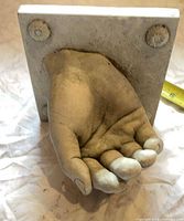 Cupped palm underside showing interior wear and square base with two decorative mounts