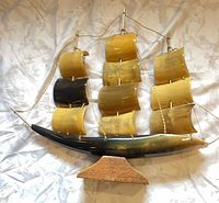 Front view of horn model ship showing sails, hull, rigging, wood stand