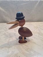 Front view of wooden bird showing hat, eyes and open beak