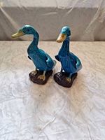 Front view of both blue glazed ceramic duck figurines