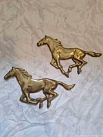 Both brass horse plaques showing design and patina