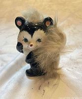 Black and white skunk figurine with faux fur tail