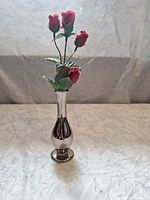 Full view of silver metallic bud vase with artificial red buds inserted
