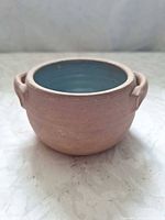 Side view of terracotta bowl showing handles, unglazed exterior, glazed interior