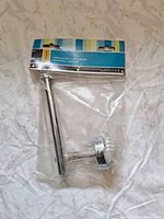 Front view of sealed Taymor chrome toilet paper holder in package