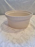 Side view of round ceramic casserole dish showing ribbed rim and glaze