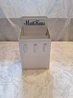 Front view showing mail slot, three hooks, logo