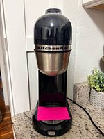 Full view of coffee maker showing overall design, color, power cord, base button