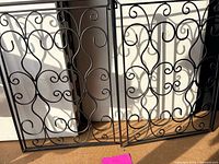 Both black metal scrollwork wall panels side by side