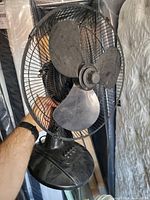 Full view of black 3-blade desk fan showing blades, grille, base and controls