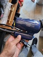 Side view of folded dark blue Conair InfinitiPremier travel hair dryer with attached cord and plug