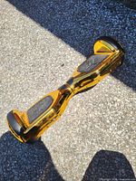 Overall view of gold chrome hoverboard showing both wheel hubs and foot pads