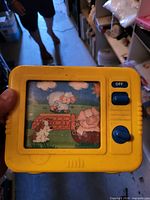 Front view of yellow handheld picture viewer showing blue controls and cartoon image