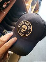 Front angle of black baseball cap showing Hook and Vice Fly Fishing Co. skull logo patch and overall condition