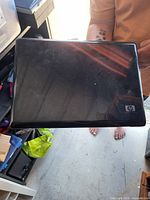 Closed laptop showing black lid with HP logo, surface scratches