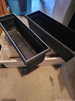 Top‐down view of three rectangular plastic planters showing color and condition
