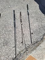 Three spinning rods laid on pavement showing full length and handles