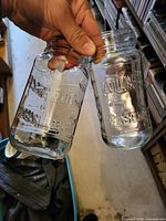 Two clear Atlas 16 oz mason jars with lids held side by side showing embossed lettering