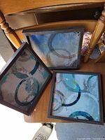 Three square abstract framed prints showing front view and frame style