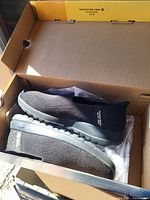 Black Skechers slip-on sneakers inside original box