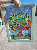 Full view of stained glass panel held outdoors showing colors and frame