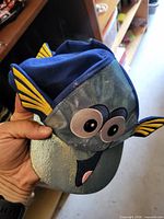 Blue and metallic toddler hat showing Dory character face and yellow fins